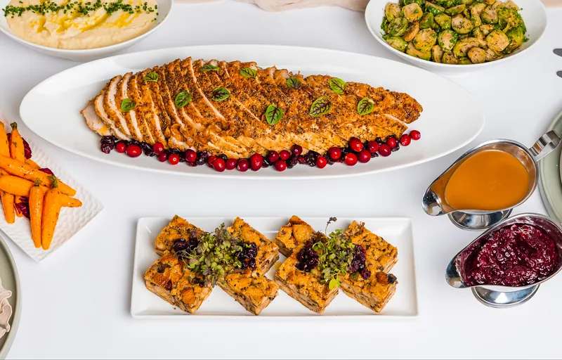 Sliced roast turkey breast with cranberries, mashed potatoes, Brussels sprouts, roasted carrots, dressing, gravy and cranberry sauce